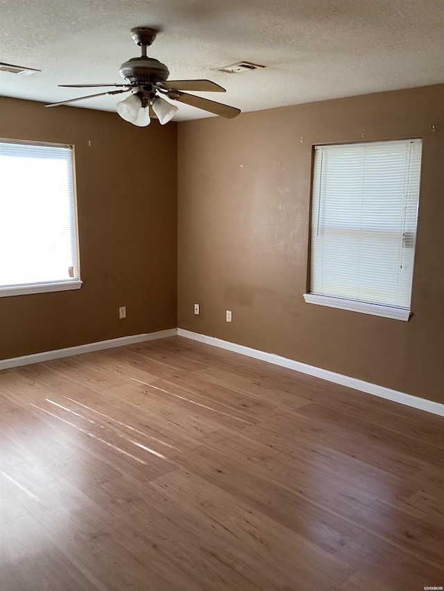 unfurnished room featuring visible vents, a textured ceiling, baseboards, and wood finished floors