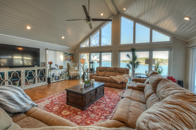 living area with plenty of natural light, high vaulted ceiling, a water view, and wood finished floors