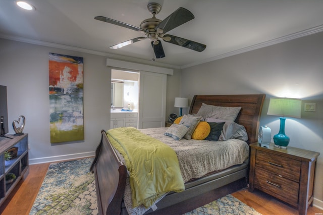 bedroom featuring baseboards, ensuite bathroom, crown molding, and wood finished floors