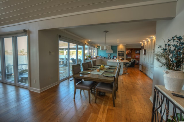 dining room with ornamental molding, baseboards, and wood finished floors