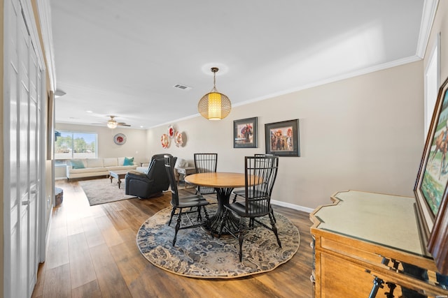 dining space featuring ceiling fan, wood finished floors, visible vents, baseboards, and ornamental molding