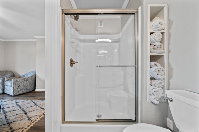 bathroom featuring toilet, a shower stall, ornamental molding, and wood finished floors