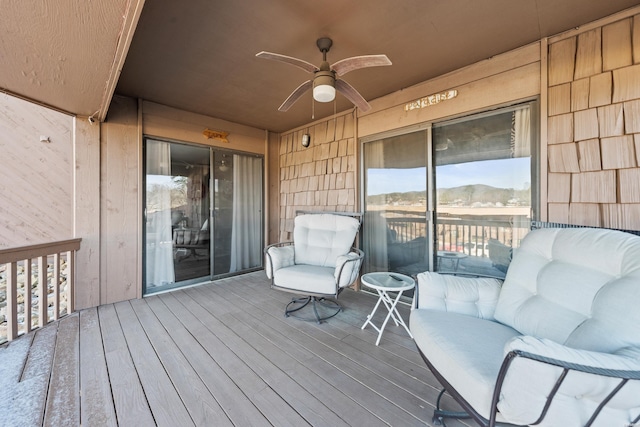 wooden terrace with a mountain view and a ceiling fan