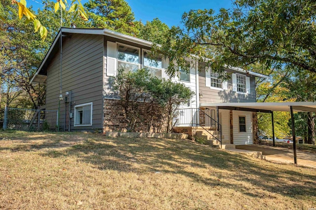 rear view of property with an attached carport, a lawn, and driveway