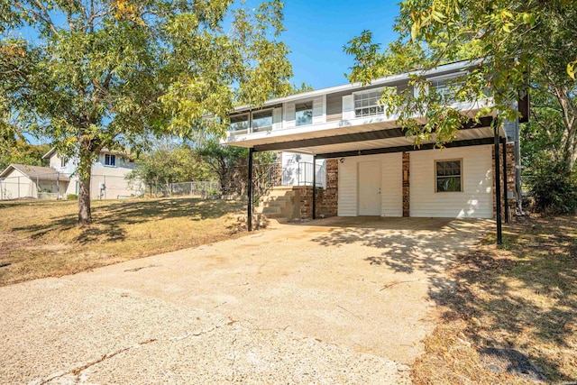 view of front facade featuring a carport, a front yard, driveway, and fence