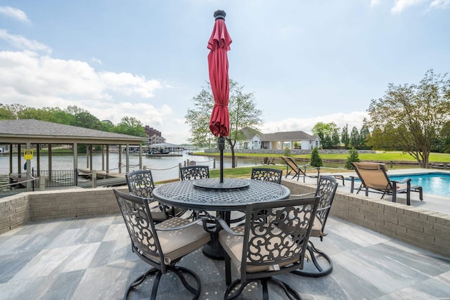 view of patio / terrace featuring outdoor dining space, an outdoor pool, and a water view