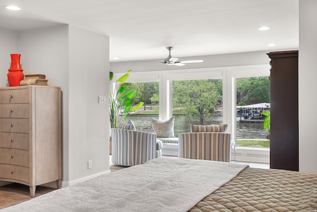 bedroom with recessed lighting, a water view, a ceiling fan, baseboards, and wood finished floors