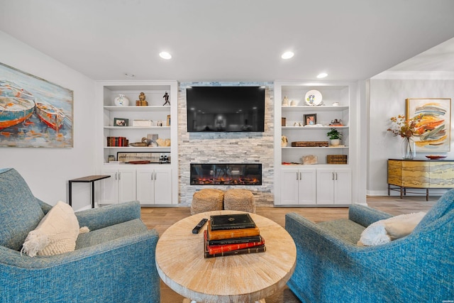 living room featuring recessed lighting, wood finished floors, a large fireplace, and built in features