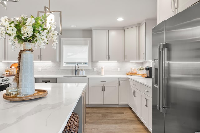 kitchen featuring a sink, light wood-style floors, high end fridge, recessed lighting, and backsplash