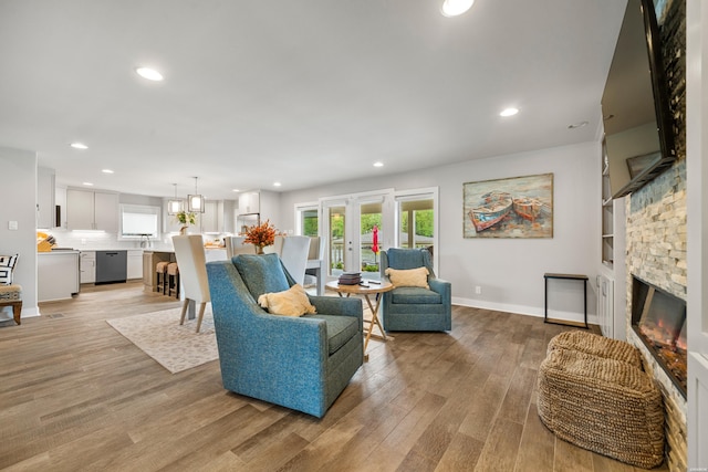 living room with baseboards, recessed lighting, a stone fireplace, and light wood finished floors