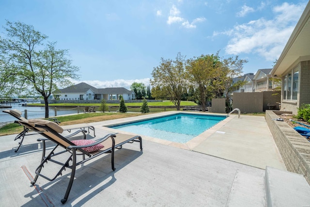 pool featuring fence, a water view, and a patio area