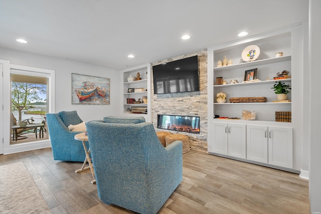 living area with recessed lighting, built in shelves, a fireplace, and light wood finished floors