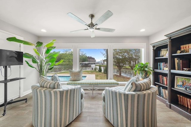 sitting room with a water view, a ceiling fan, and recessed lighting