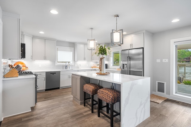 kitchen with a sink, appliances with stainless steel finishes, recessed lighting, wood finished floors, and backsplash