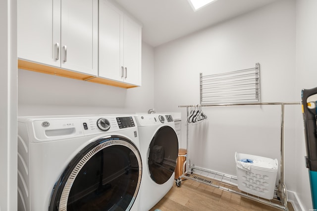 laundry room featuring wood finished floors, cabinet space, and washing machine and dryer