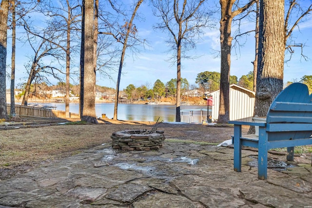 view of yard with an outdoor fire pit, a water view, and fence