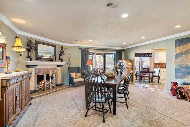 dining room featuring a fireplace, visible vents, crown molding, and light colored carpet