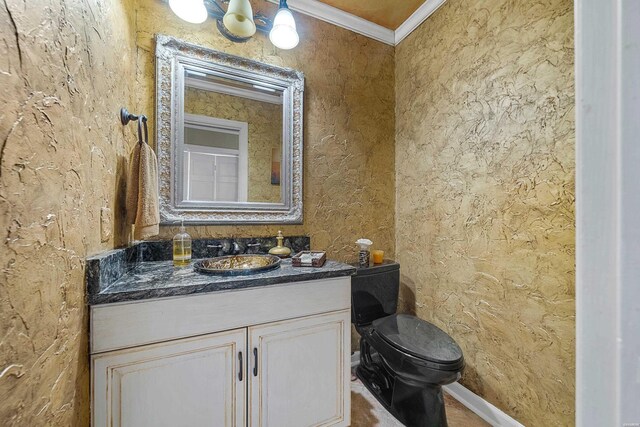 bathroom featuring toilet, baseboards, ornamental molding, and vanity