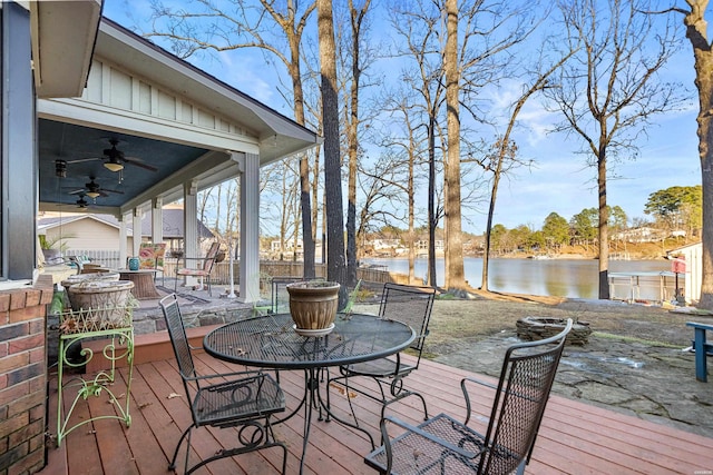 wooden deck with a water view, ceiling fan, fence, and outdoor dining area