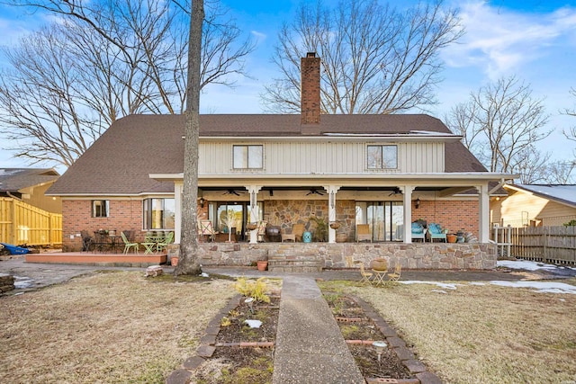 rear view of house with a lawn, a chimney, fence, and a ceiling fan