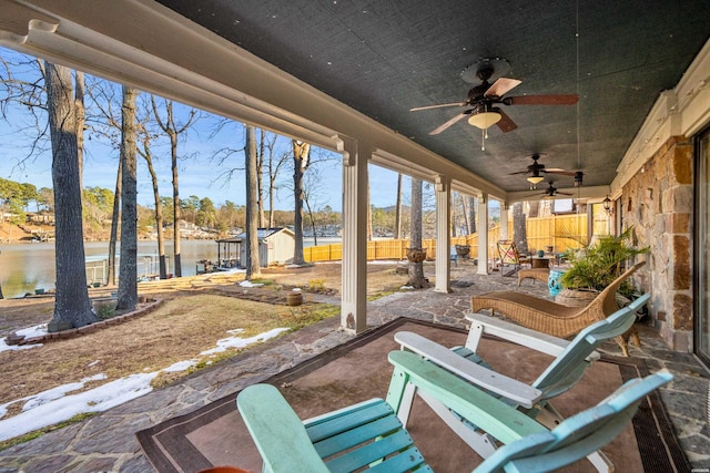 view of patio featuring an outbuilding, a fenced backyard, a storage shed, a water view, and a ceiling fan