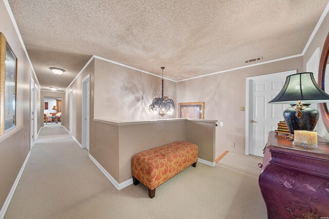 hallway with a textured ceiling, light colored carpet, visible vents, baseboards, and ornamental molding