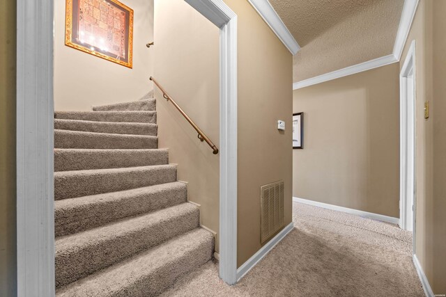 stairway featuring baseboards, visible vents, carpet, a textured ceiling, and crown molding