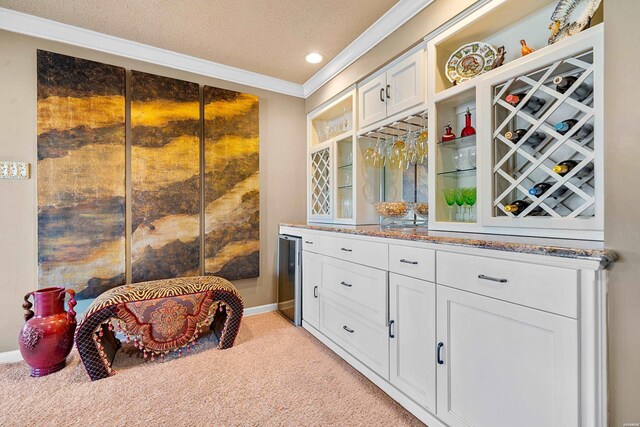 bar featuring a textured ceiling, wine cooler, light colored carpet, ornamental molding, and a dry bar