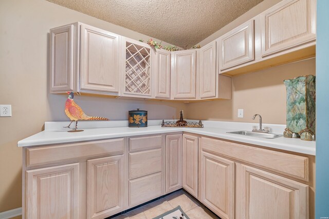 kitchen with light countertops, a sink, a textured ceiling, and light tile patterned flooring