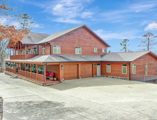 chalet / cabin with driveway, an attached garage, and a shingled roof