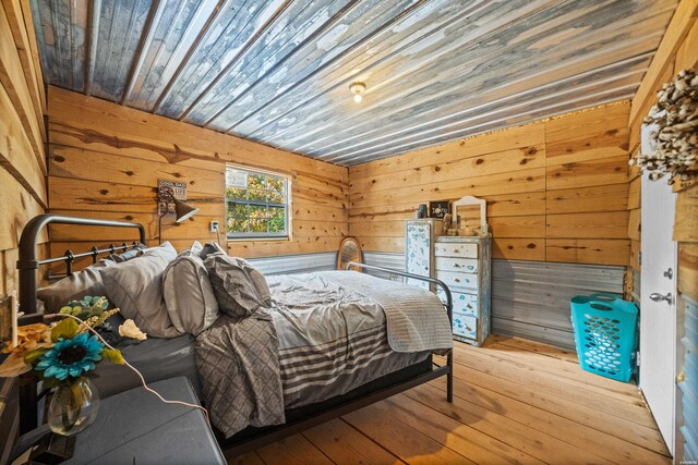 bedroom with wooden ceiling, wooden walls, and light wood finished floors