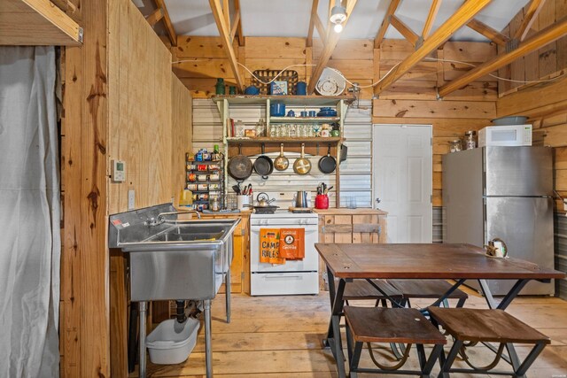 kitchen with white appliances, wooden walls, and light wood-style floors