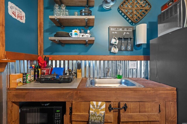 kitchen with black microwave, a sink, and open shelves