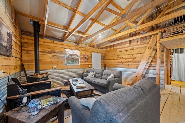 living area with lofted ceiling with beams, wood finished floors, a wood stove, and wooden walls