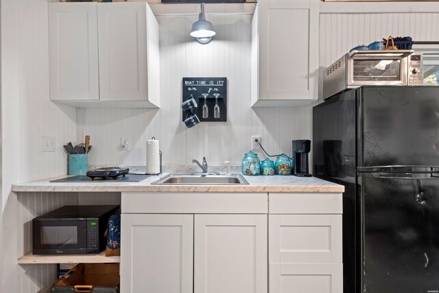 kitchen featuring a sink, black appliances, light countertops, and white cabinetry