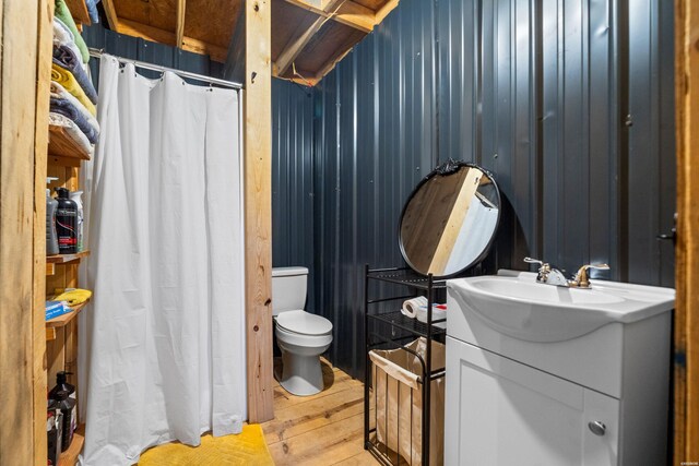 full bathroom with wood walls, vanity, toilet, and wood finished floors