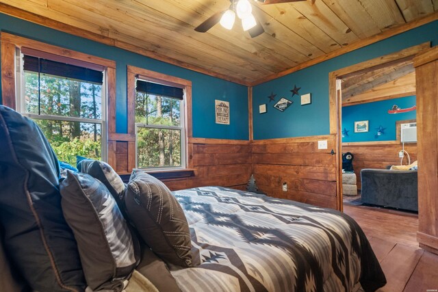 bedroom with wood ceiling, wooden walls, wood finished floors, and wainscoting