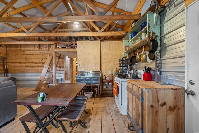 miscellaneous room featuring lofted ceiling, light wood-type flooring, and wooden walls