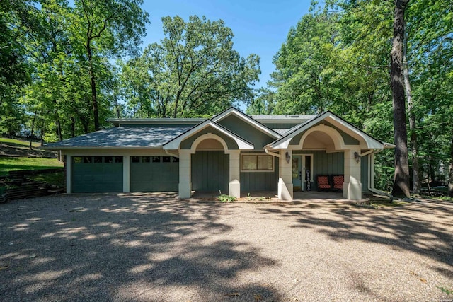 view of front of home featuring a garage, roof with shingles, and gravel driveway