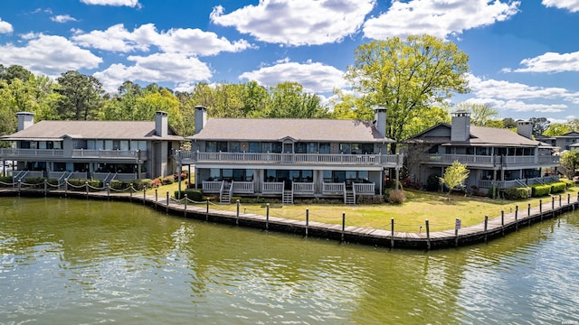 rear view of property featuring a lawn and a water view