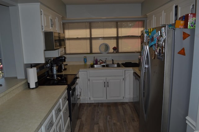 kitchen with a sink, white cabinetry, light countertops, appliances with stainless steel finishes, and dark wood-style floors