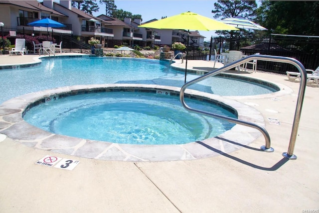 community pool featuring a community hot tub and fence