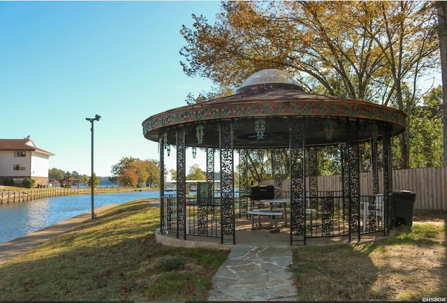 surrounding community with a gazebo, a lawn, a water view, and fence