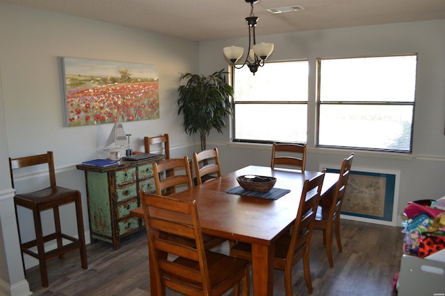 dining space featuring dark wood-style flooring, visible vents, and a notable chandelier