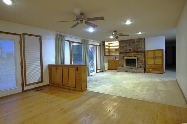 1 Alora Ln, Hot Springs Village, AR 71909 - unfurnished living room with visible vents, baseboards, ceiling fan, a stone fireplace, and light wood-style floors
