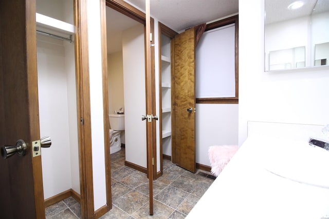 1 Alora Ln, Hot Springs Village, AR 71909 - bathroom with baseboards, visible vents, toilet, a walk in closet, and a sink