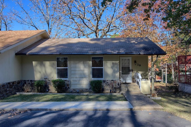 view of front of home with a shingled roof, stone siding, and a porch