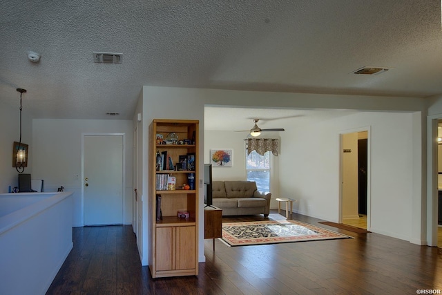 living room featuring ceiling fan, dark wood finished floors, and visible vents