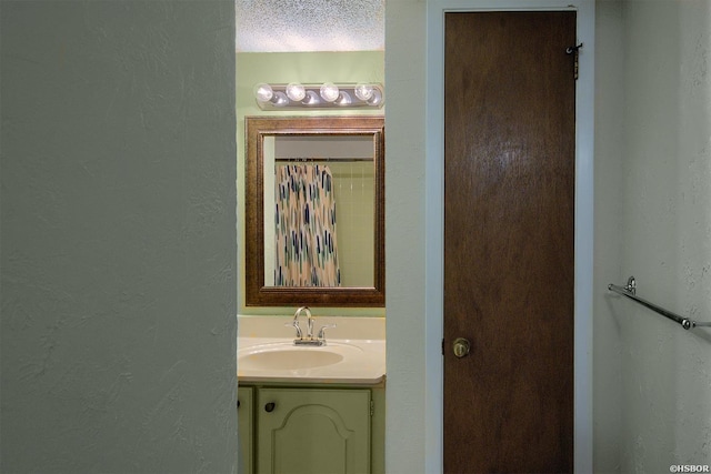 bathroom with a textured wall, a textured ceiling, and vanity