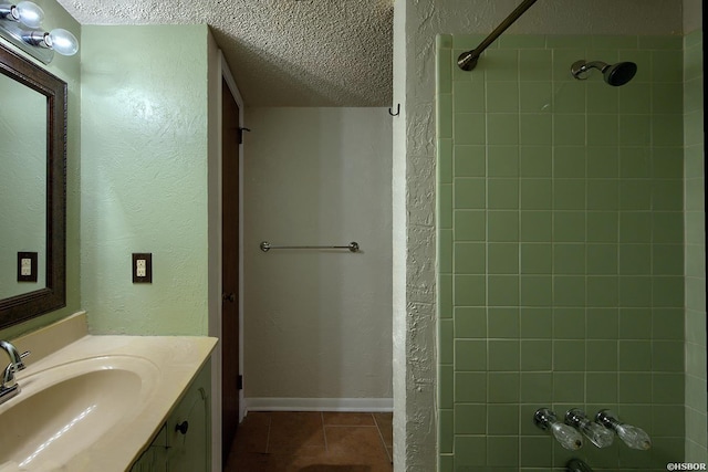 bathroom with a shower, a textured ceiling, vanity, tile patterned flooring, and baseboards